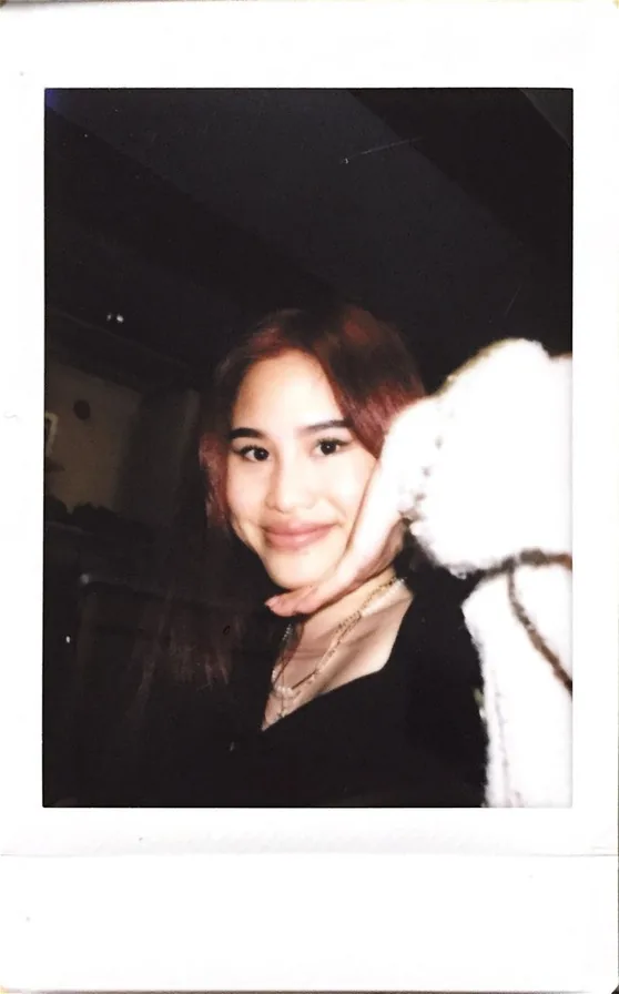 Instant photo of Romana Ta smiling, with a white fluffy sleeve